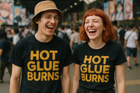 Two people are standing side by side, both laughing and wearing matching black t-shirts with the text 