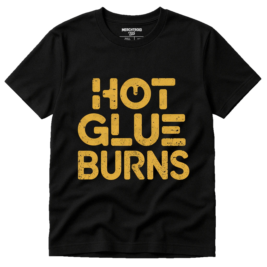 A black t-shirt with the words "HOT GLUE BURNS" printed in bold, distressed yellow letters.