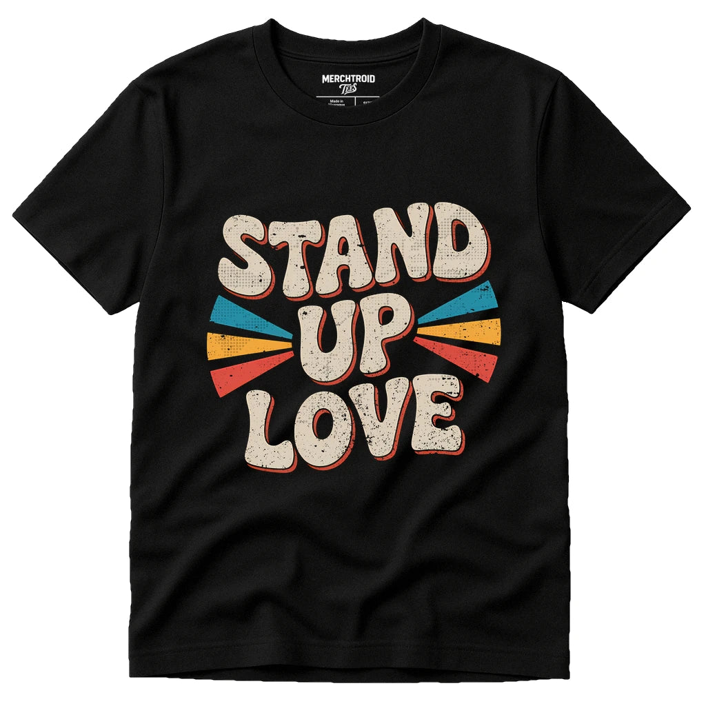A black t-shirt with a retro-style design featuring the words "STAND UP LOVE" in bold, textured letters. The text is surrounded by colorful, fan-like shapes in red, blue, orange, and yellow.