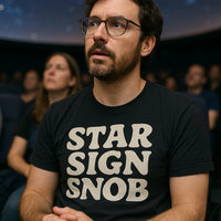 A person with a beard and glasses is wearing a black T-shirt with the text 