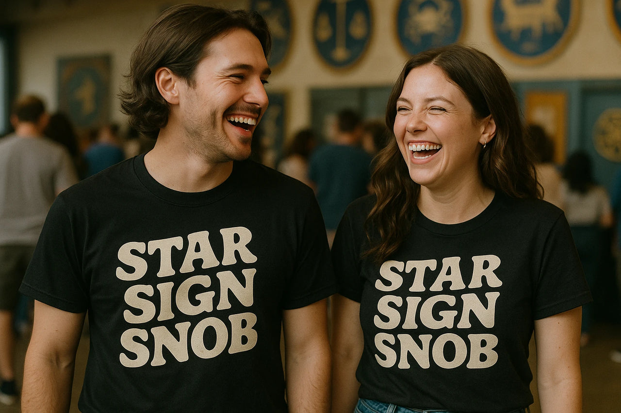 A man and a woman are standing and laughing together. Both are wearing black T-shirts with the text "STAR SIGN SNOB" in large white letters. The background shows a room with people and decorative circular symbols on the wall.