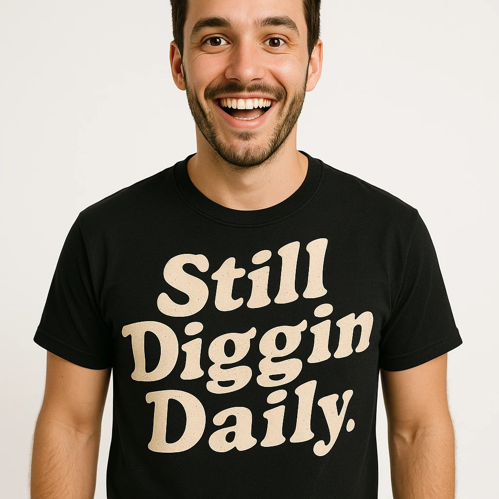 Close-up of the "Still Diggin Daily" cream print on a premium Bella+Canvas black hip hop tee shirts