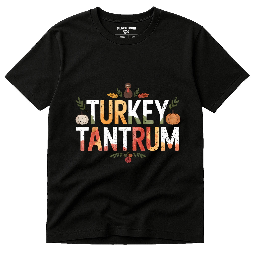 A black t-shirt with the words "TURKEY TANTRUM" printed in large, colorful letters. The design features autumn-themed graphics including a pumpkin, leaves, and a small red turkey illustration. The brand "MERCHTROIOD" is printed on the inside label.