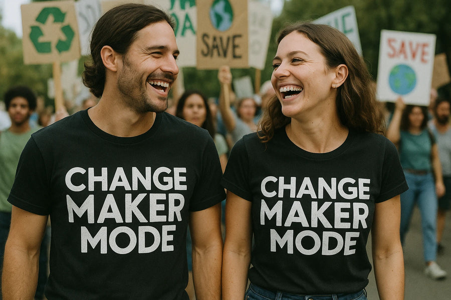 A man and woman are smiling at each other while walking in a protest or rally. Both are wearing black T-shirts with the text "CHANGE MAKER MODE." People in the background are holding signs with environmental messages, including a recycling symbol and the word "SAVE" above a depiction of the Earth.