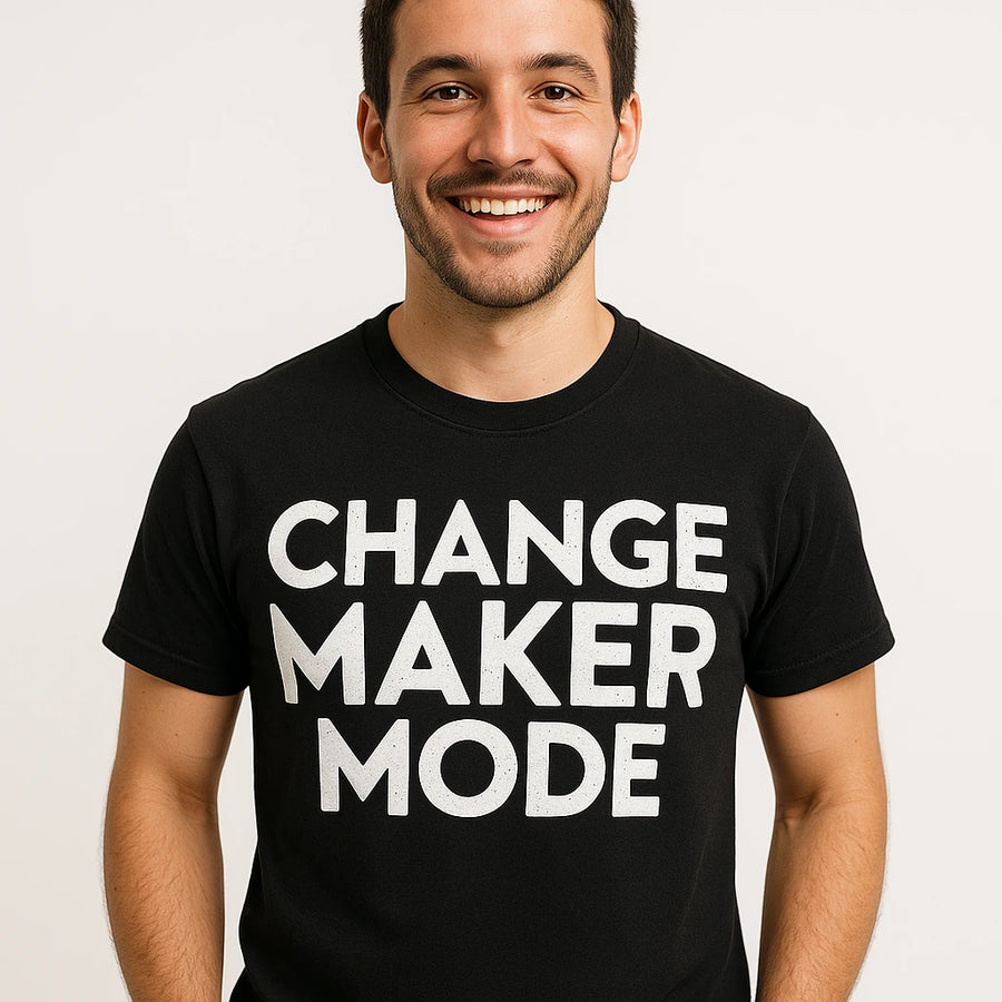 A person wearing a black t-shirt with the text "CHANGE MAKER MODE" printed in white capital letters. The person has short dark hair and is smiling, standing against a plain background.