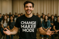 A person is smiling with open arms, wearing a black t-shirt with the text 