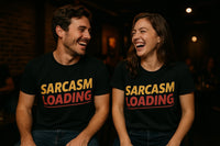 A man and a woman are sitting and laughing together. Both are wearing black T-shirts with the text 