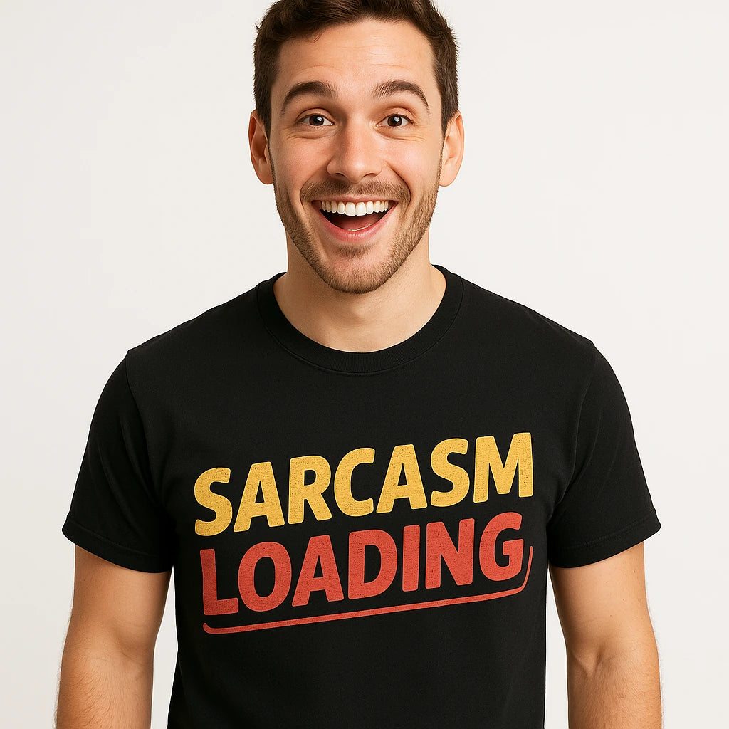 A person with short, dark hair is smiling widely while wearing a black T-shirt that has the words "SARCASM LOADING" printed in large yellow and red letters across the chest. The background is plain white.