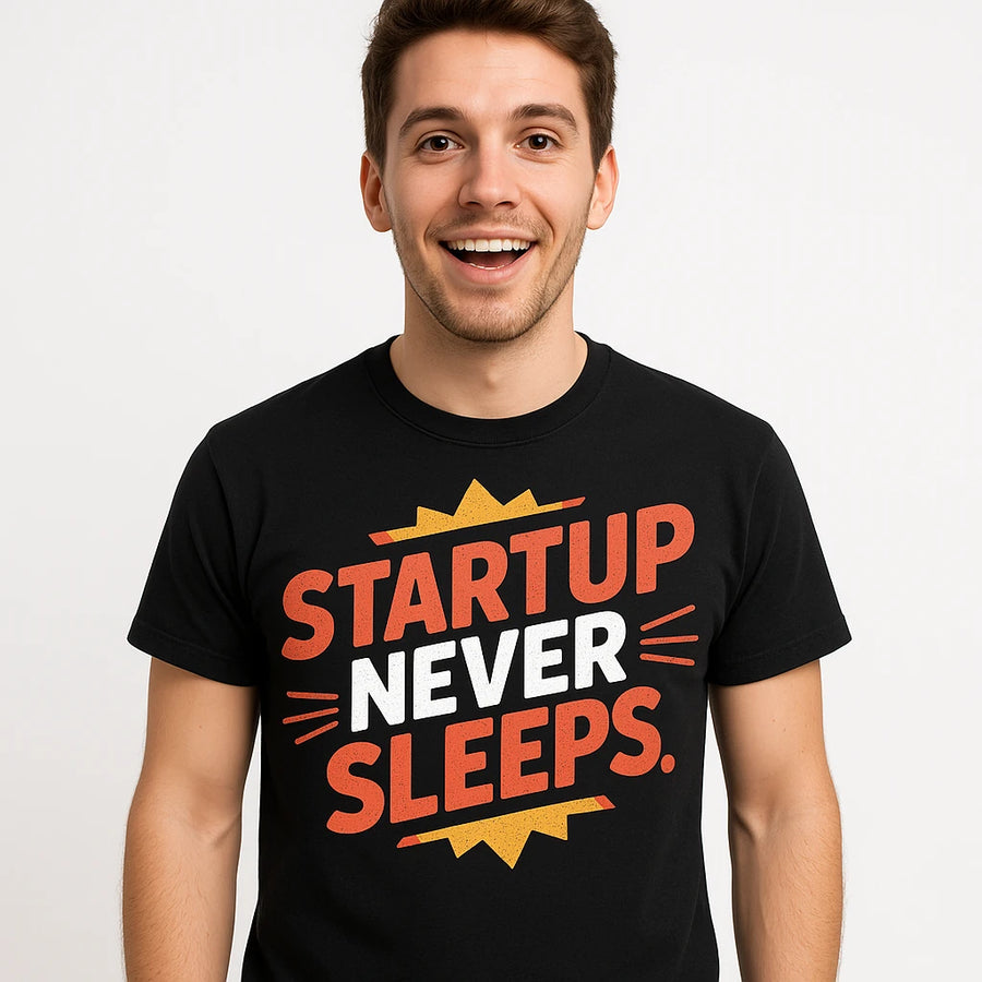 A person is smiling while wearing a black T-shirt with bold, colorful text. The text on the shirt reads "STARTUP NEVER SLEEPS" in red and white with yellow accents. The image has a light background.