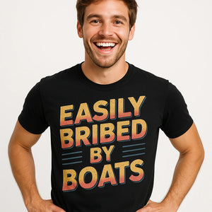 Close-up of the "Easily Bribed By Boats" gold print on a premium Bella+Canvas black t shirt boat neck