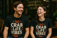 A man and a woman are sitting together, both laughing and wearing matching black t-shirts with the text 