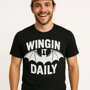 Close-up of the "Wingin It Daily" white print on a premium Bella+Canvas black batwing tshirt