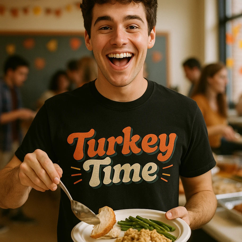 A person is smiling widely, wearing a black T-shirt with the text "Turkey Time" printed on it in bold, festive lettering. They are holding a plate with food including turkey slices, green beans, and stuffing. In the background, people are mingling in a room decorated with autumn-themed decor.