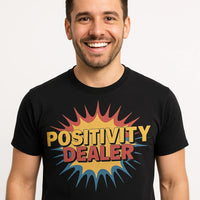 A person with short dark hair and a beard, smiling broadly. They are wearing a black T-shirt with the words 