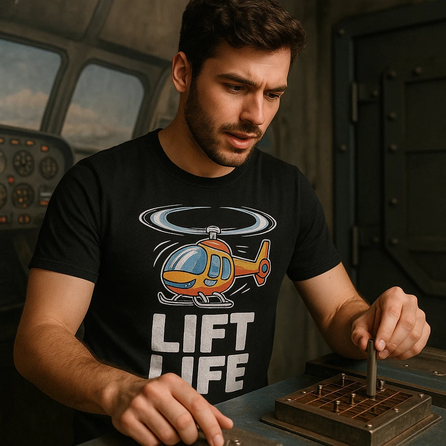 A person with a beard and short hair is wearing a black t-shirt with a colorful helicopter design and the text "LIFT LIFE." They are focused on manipulating a vertical cylindrical object on a grid-like board, set in what appears to be a control room or cockpit environment.