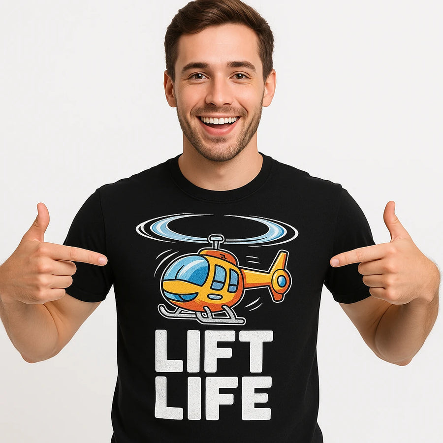 A smiling person with short hair wearing a black T-shirt featuring a colorful illustration of a helicopter above the text "LIFT LIFE." The person is pointing at the design on their shirt with both hands.