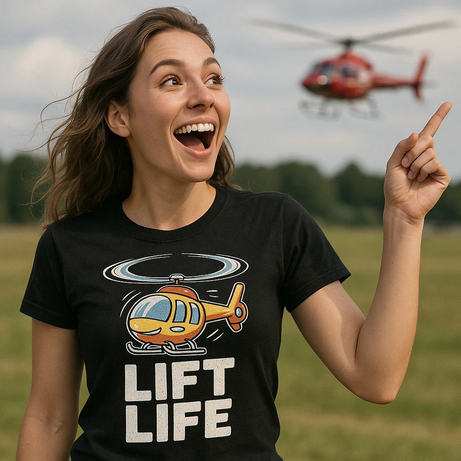 A person with long brown hair, wearing a black T-shirt with a cartoon helicopter design and the words "LIFT LIFE," is smiling broadly and pointing to the sky. In the background, a red helicopter is flying. The setting appears to be an open grassy field.