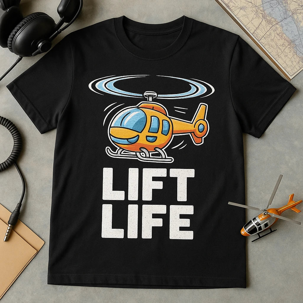 A black t-shirt featuring a colorful cartoon helicopter above the words "LIFT LIFE." The shirt is laid out flat on a surface with a pair of headphones, a helicopter model, and a map nearby.