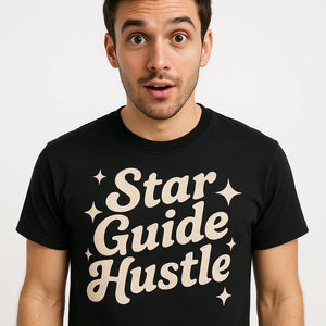 Close-up of the "Star Guide Hustle" cream print on a premium Bella+Canvas black astrology shirts
