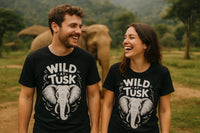 A man and woman are standing outdoors, smiling at each other. They both wear black T-shirts featuring a graphic of an elephant with the text 