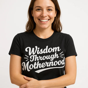 Close-up of the "Wisdom Through Motherhood" white print on a premium Bella+Canvas black mama life t shirt