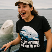 A person with long hair and a wide smile is standing on a boat wearing a beige cap and a black t-shirt featuring an illustration of a whale and the text 