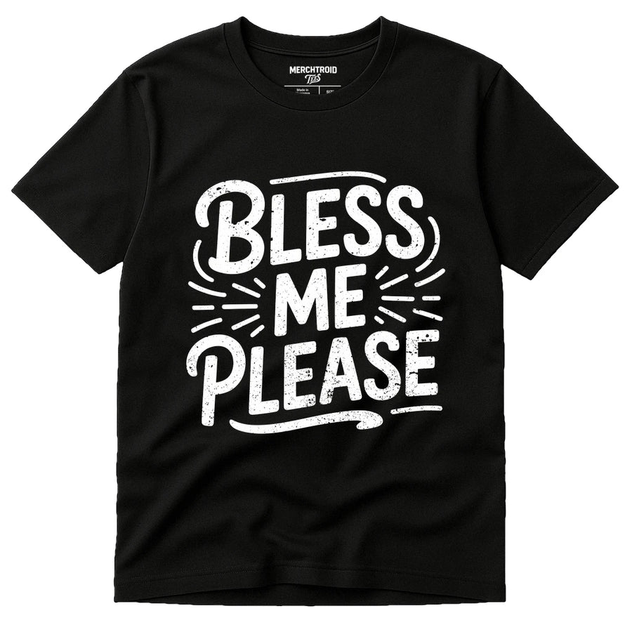 A black t-shirt with bold white text reading "Bless Me Please" in a playful font with decorative elements around the words.