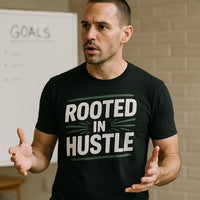 A person with short hair is speaking while gesturing with their hands. They are wearing a black t-shirt with the text 