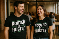 A man and a woman are standing indoors, both smiling broadly and wearing black T-shirts with the text 