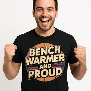 Close-up of the "Bench Warmer and Proud" beige print on a premium Bella+Canvas black basketball t shirt