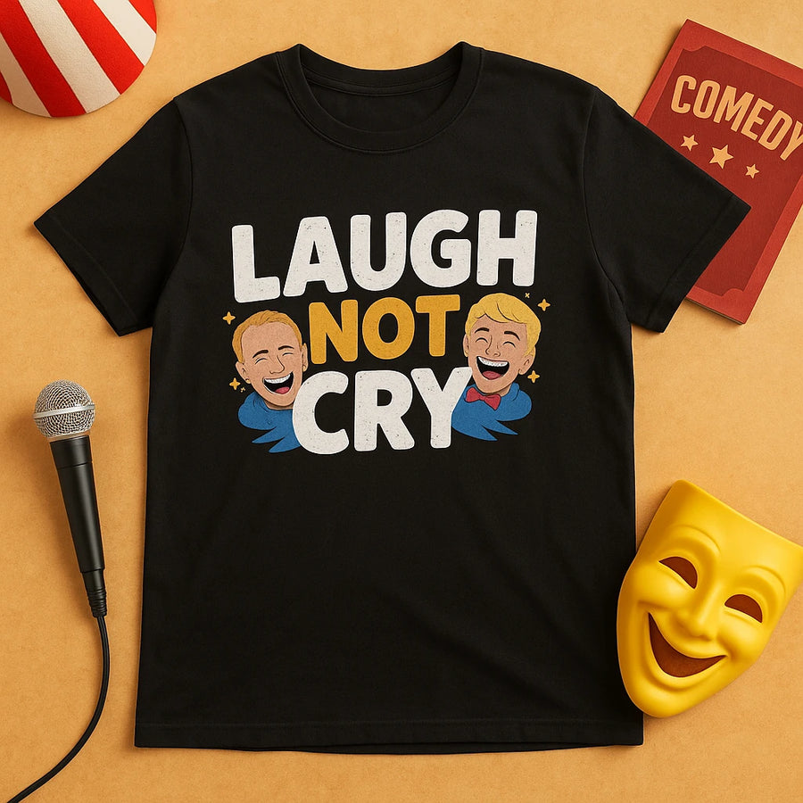 A black t-shirt with the text "LAUGH NOT CRY" written on it in white, yellow, and white bold letters, respectively. Below the text are illustrations of two laughing faces, both wearing blue shirts and one with a red bow tie. Around the t-shirt are various comedy-themed objects, including a microphone, a comedy book, a yellow comedy mask, and a red and white striped hat.