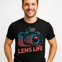 A smiling person wearing a black t-shirt with a colorful graphic of a camera and the text 