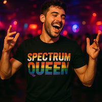 A person with short dark hair and a beard is smiling and gesturing with both hands, eyes closed in a lively manner. They're wearing a black T-shirt with the text 