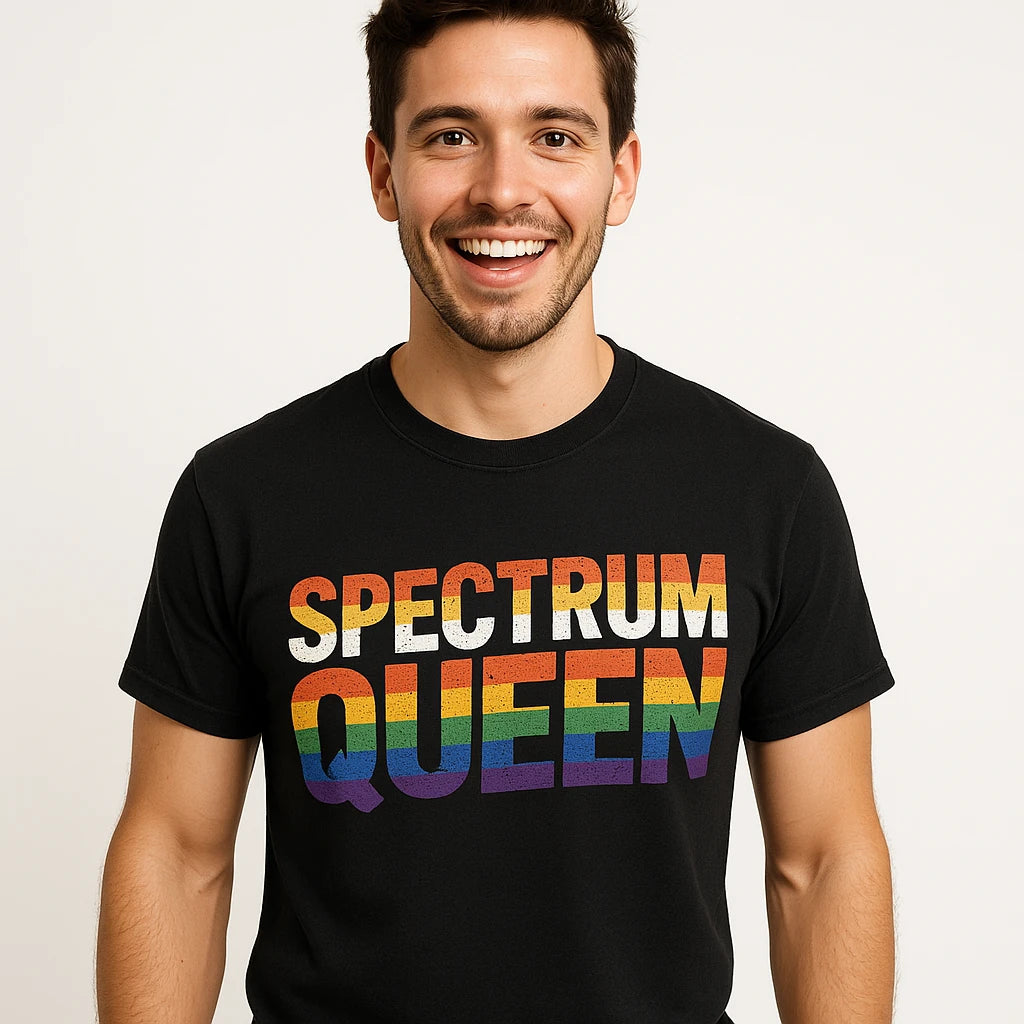 A person with short dark hair and a beard is smiling, wearing a black t-shirt with the words "SPECTRUM QUEEN" in rainbow colors. The background is a neutral white.