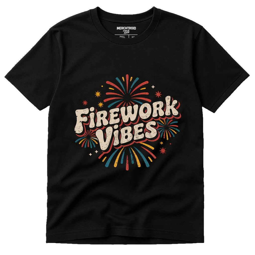 A black t-shirt featuring colorful illustrations of fireworks around the bold, stylized text "Firework Vibes" in the center. The shirt has a casual, festive design.