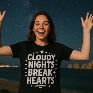 Lifestyle shot of the "Cloudy Nights Break Hearts" black stargazing t shirt in a real-world setting