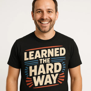Close-up of the "Learned the Hard Way" beige print on a premium Bella+Canvas black dad shirts