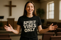 A person with long brown hair is smiling widely, wearing a black T-shirt with the words 