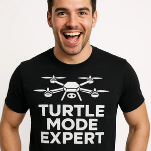Close-up of the "Turtle Mode Expert" white print on a premium Bella+Canvas black drone t shirt