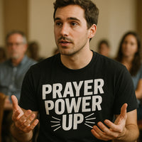 A person with short dark hair and a beard is wearing a black t-shirt with the text 