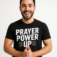 A person with a beard and mustache is smiling and wearing a black t-shirt with the text 