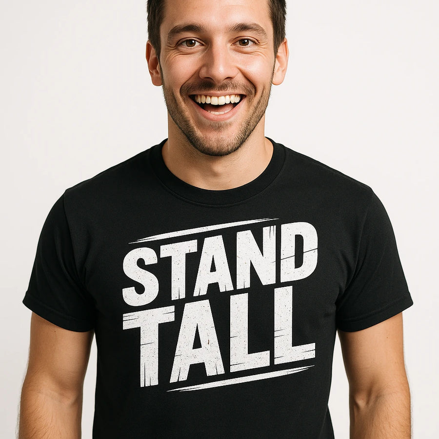 A smiling person wearing a black t-shirt with bold white text that reads "STAND TALL." The background is plain and light-colored.