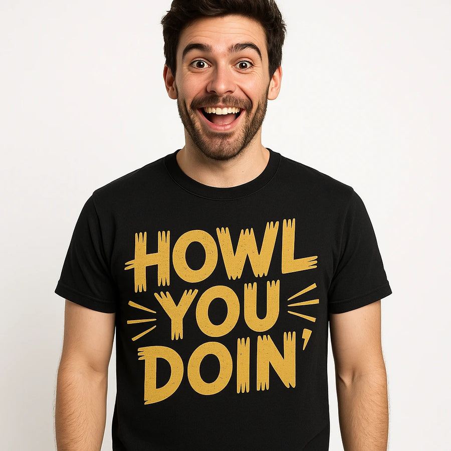 A person with short dark hair and a beard is wearing a black t-shirt with the text "HOWL YOU DOIN'" in large yellow letters. The person is smiling widely and standing against a plain white background.