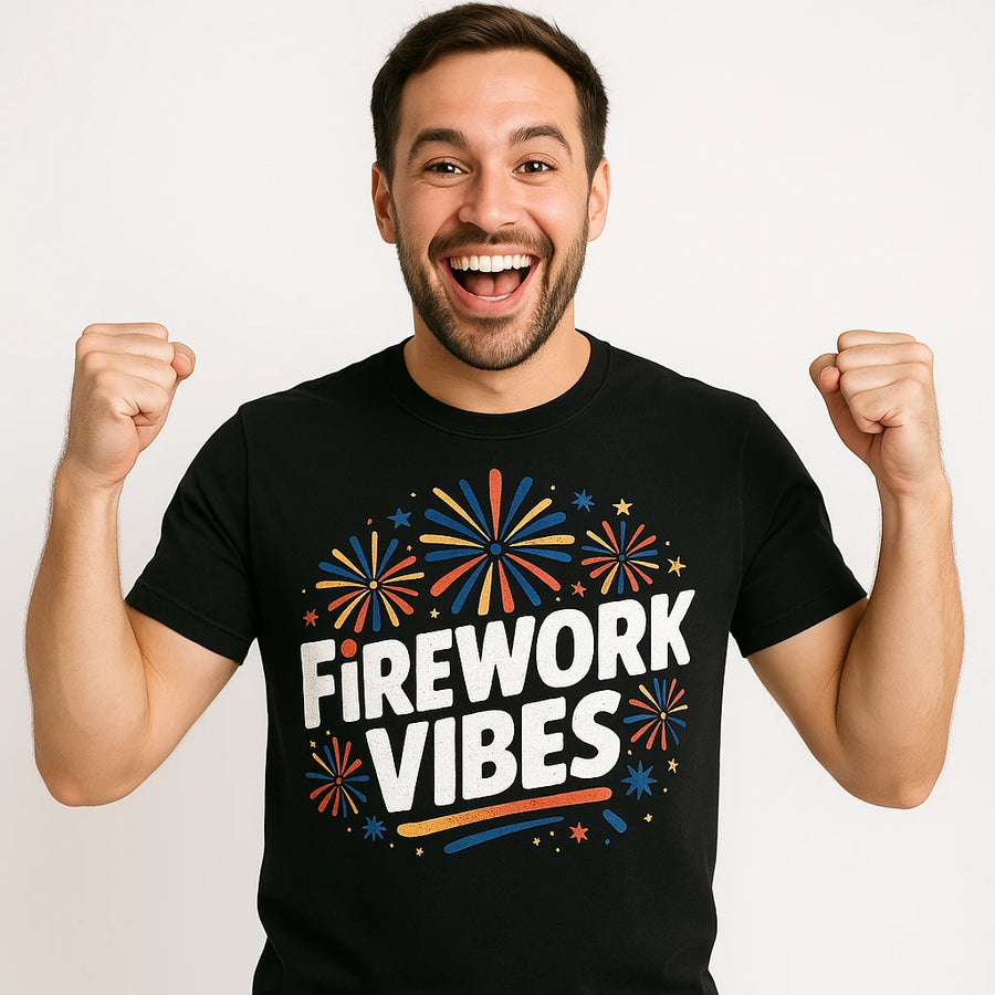 A person with a beard is smiling widely and raising their fists in excitement. They are wearing a black t-shirt with colorful firework designs around the text "FIREWORK VIBES." The background is plain white.