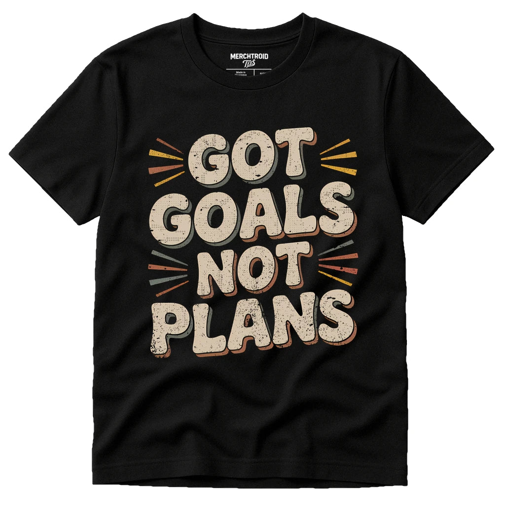 A black t-shirt with bold, stylized text on the front that reads "GOT GOALS NOT PLANS." The text is surrounded by decorative lines in various colors.
