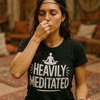 A person is performing a breathing exercise with eyes closed, pressing one nostril with a finger. They are wearing a black t-shirt with the phrase 