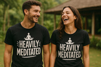 A man and a woman are standing outdoors, both wearing black t-shirts with a figure in a meditation pose and the text 