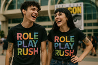 Two people are standing side by side, laughing together. They are both wearing black T-shirts with the text 