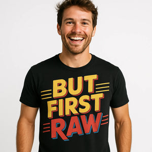 Close-up of the "But First Raw" red print on a premium Bella+Canvas black photography tee