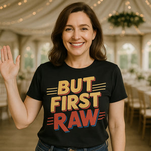 Lifestyle shot of the "But First Raw" black photography tee in a real-world setting